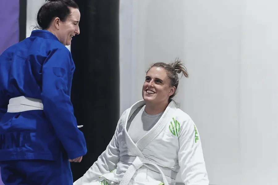 Two women laughing together in their gis after training