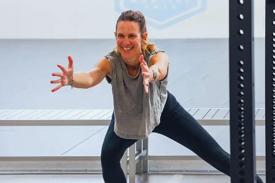 A woman mid-lunge and smiling in a fitness session